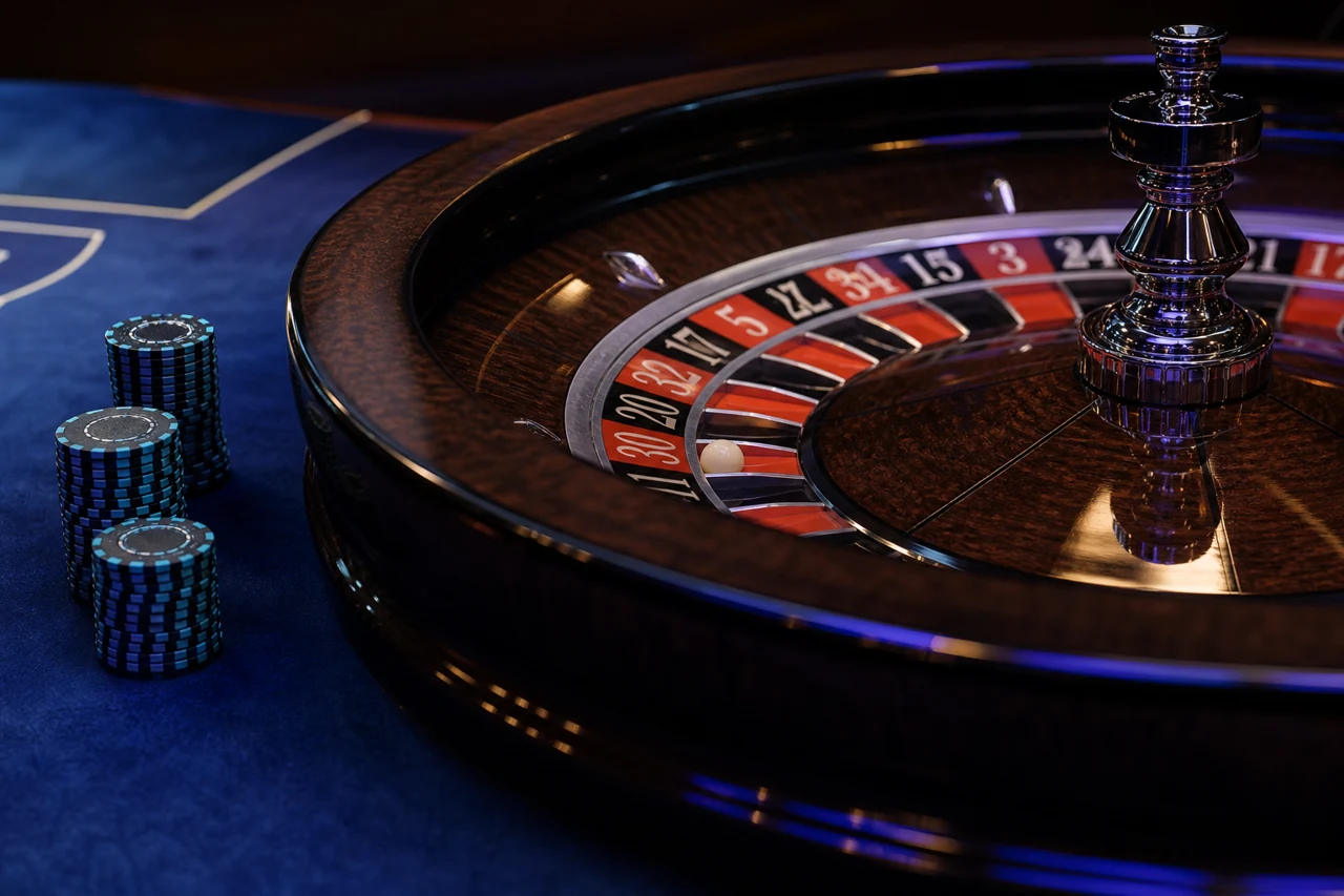 Photorealistic editorial macro photograph of a polished roulette wheel, navy felt and three modest cyan-edged clay-chip stacks, moody deep blue light